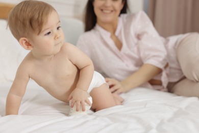 Photo of Mother with her little baby and feeding bottle of milk on bed at home, closeup