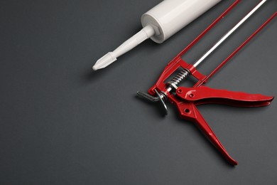 Photo of Glue gun and tube on gray background, above view. Space for text