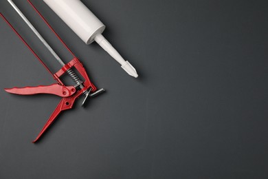 Photo of Glue gun and tube on gray background, flat lay. Space for text