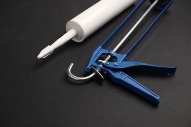 Photo of Glue gun and tube on black background, closeup