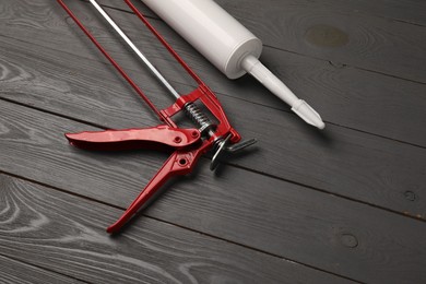 Photo of Glue gun and tube on gray wooden background, closeup