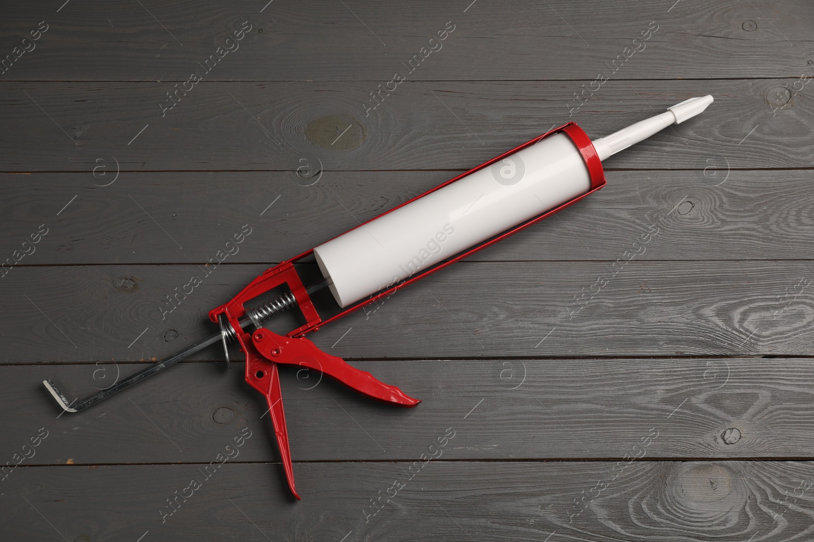 Photo of Glue gun on gray wooden background, top view