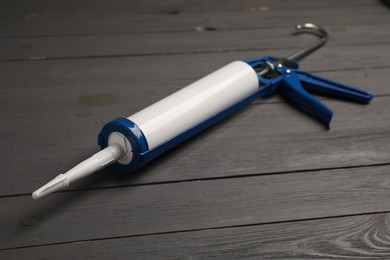 Photo of Glue gun on gray wooden background, closeup