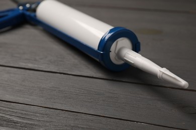 Photo of Glue gun on gray wooden background, closeup