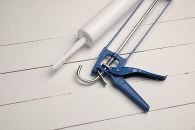 Photo of Glue gun and tube on white wooden background, above view