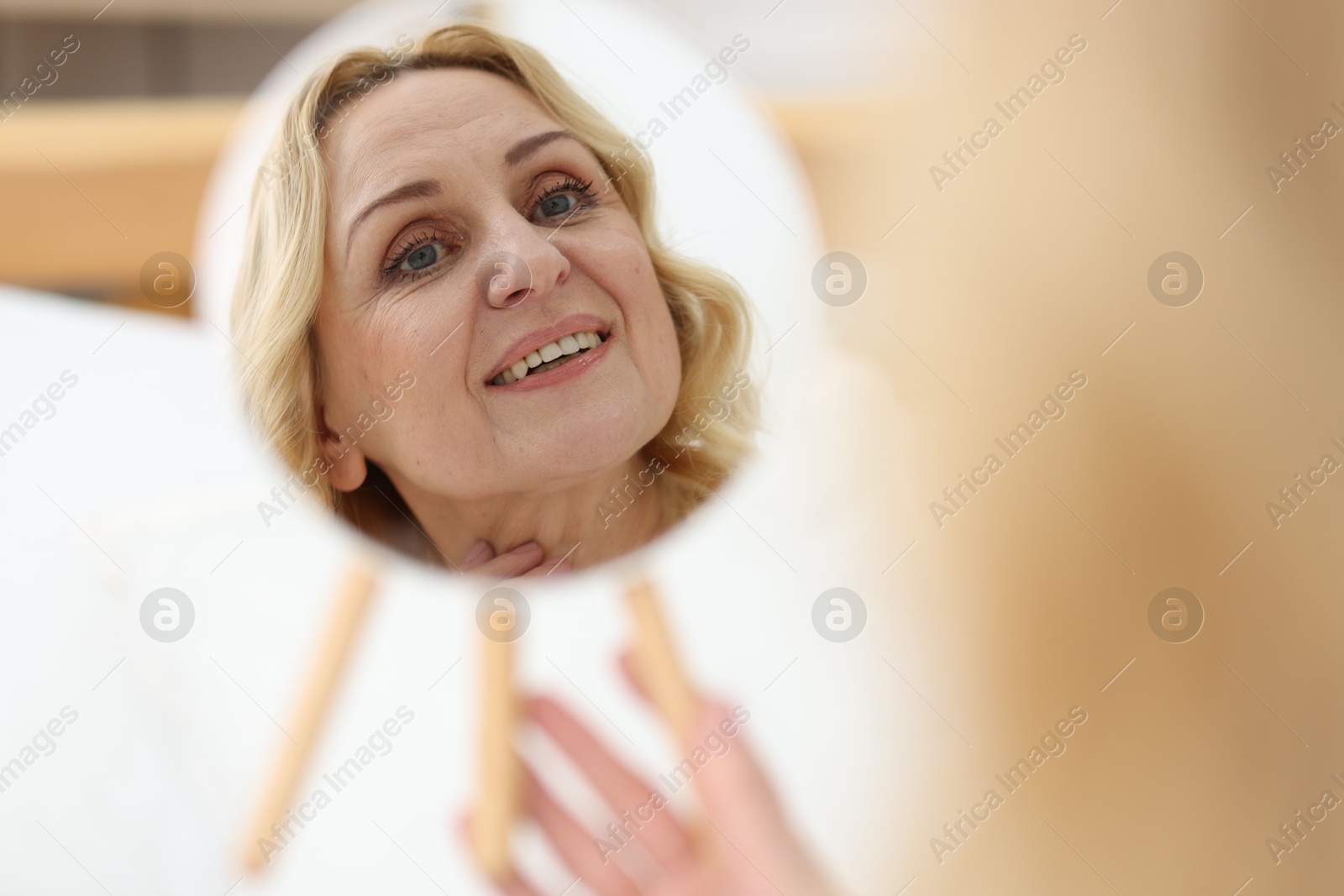 Photo of Smiling middle aged woman with round mirror on blurred background