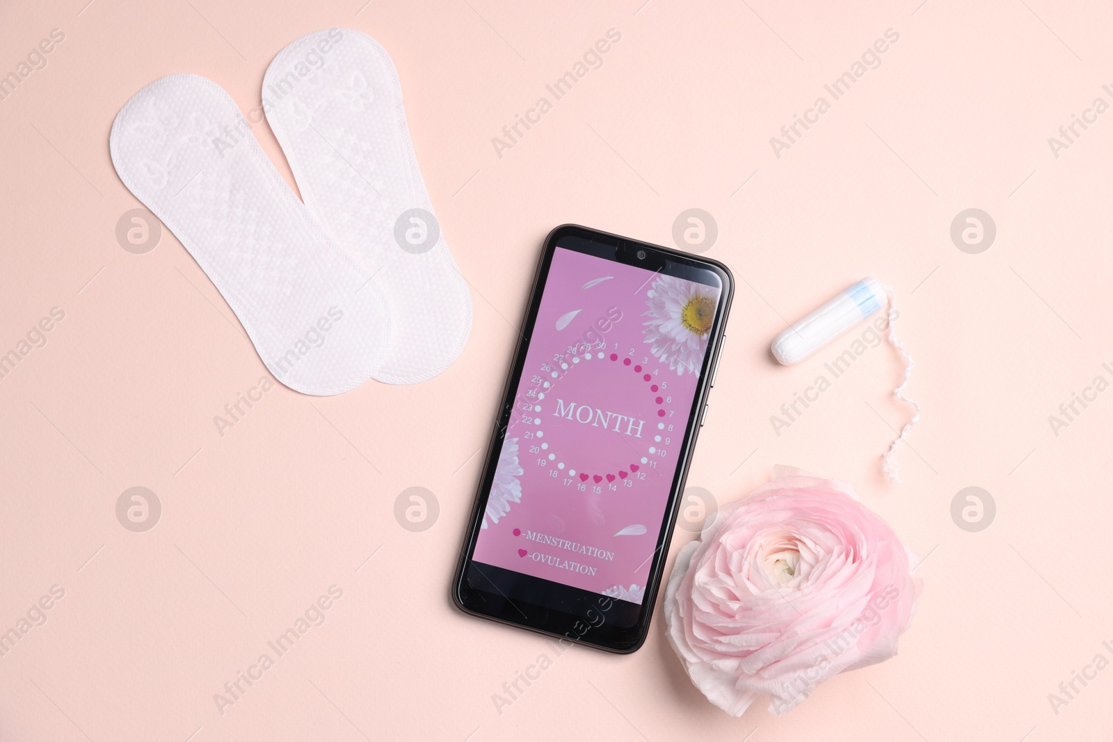 Photo of Smartphone with period calendar application, menstrual products and flower on beige background, flat lay