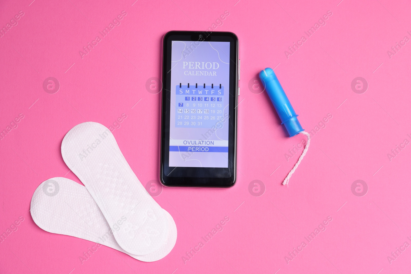 Photo of Smartphone with period calendar application and menstrual products on pink background, flat lay