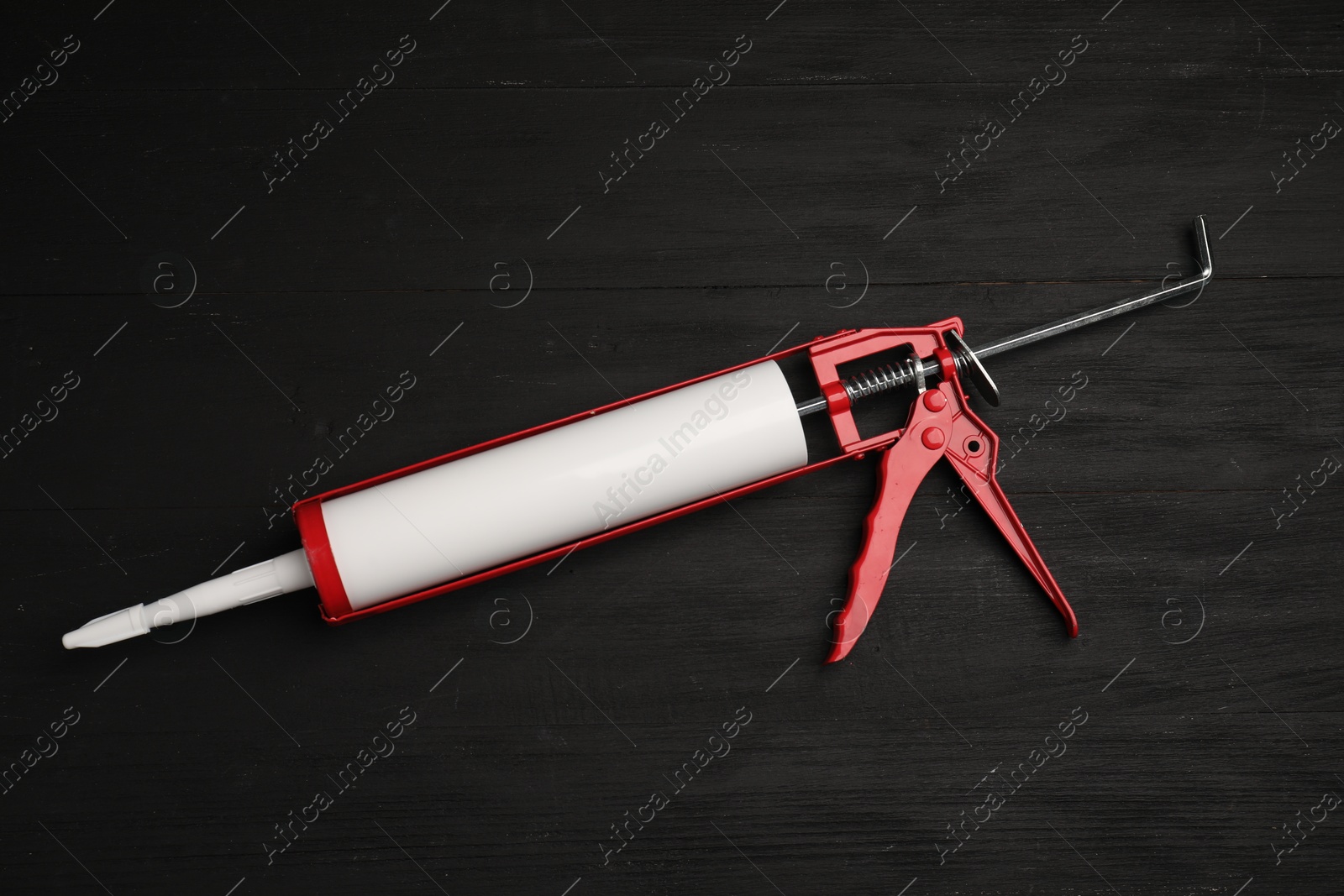 Photo of One glue gun on black wooden background, top view. Construction tool