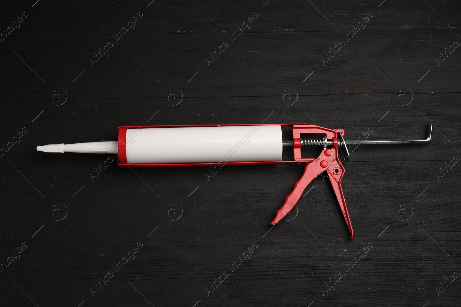 Photo of One glue gun on black wooden background, top view. Construction tool