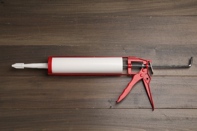 Photo of One glue gun on wooden background, top view. Construction tool