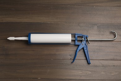 One glue gun on wooden background, top view. Construction tool