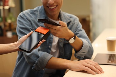 Photo of Man paying with smartphone via terminal in cafe, closeup