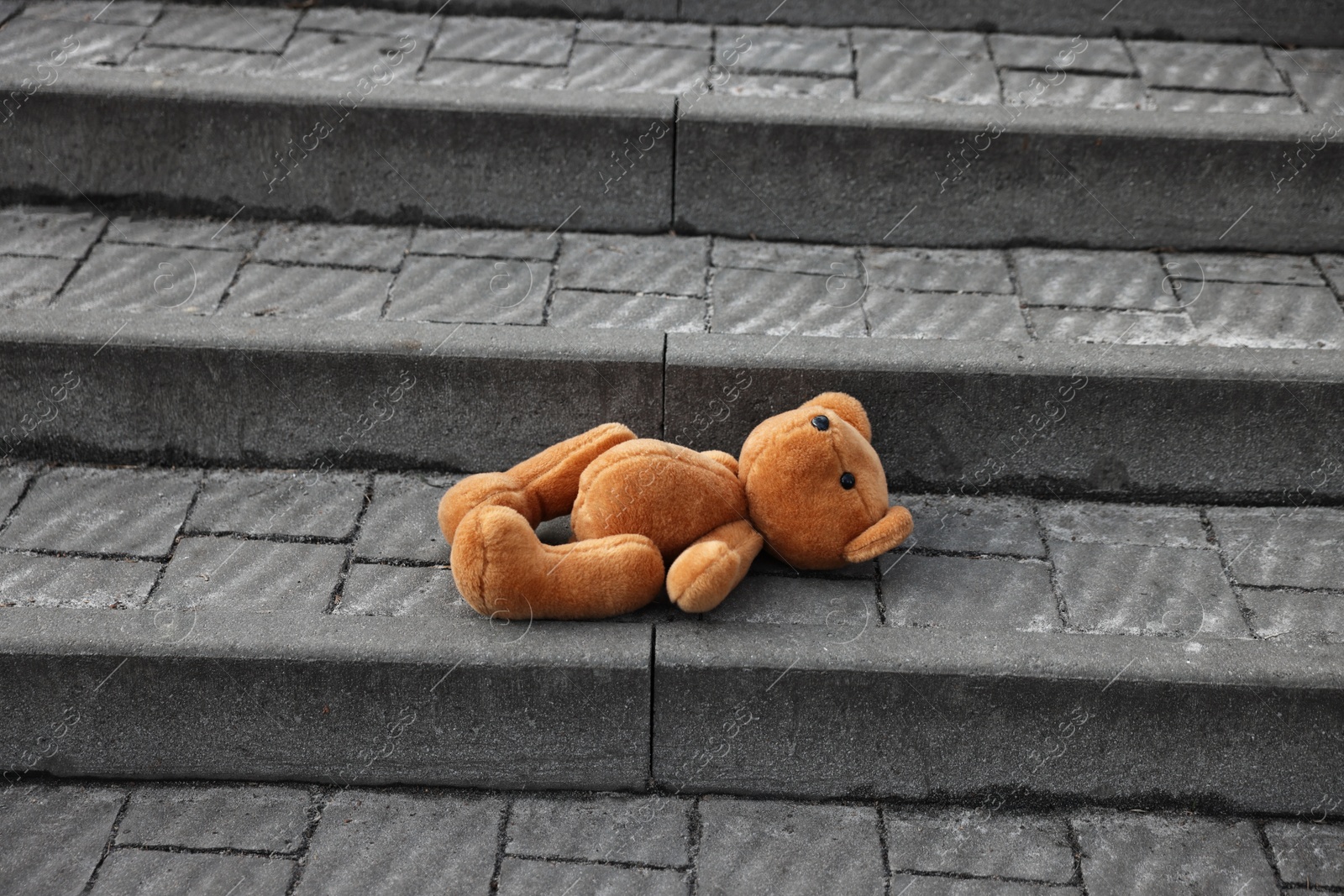 Photo of Lost brown teddy bear on stairs outdoors