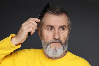 Photo of Handsome man combing his hair on dark grey background