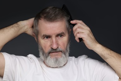 Photo of Handsome man combing his hair on dark grey background