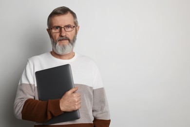 Photo of Mature man with laptop on light grey background, space for text