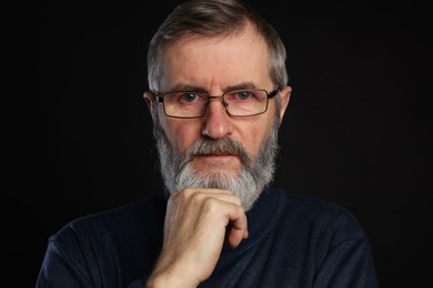 Photo of Portrait of mature man in glasses on black background