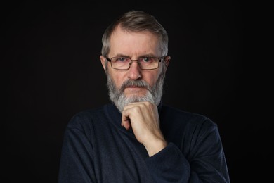 Photo of Portrait of mature man in glasses on black background