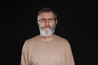 Photo of Portrait of mature man in glasses on black background