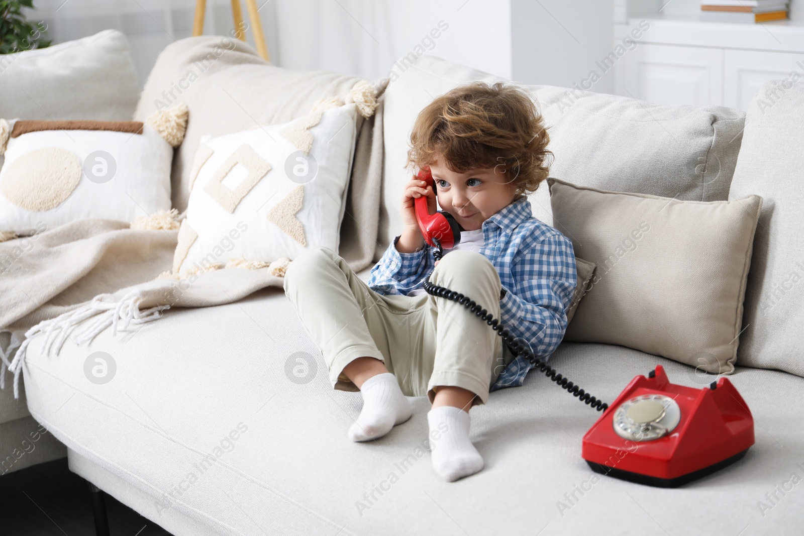 Photo of Cute little boy with telephone on sofa indoors