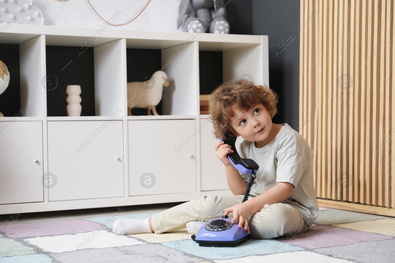 Photo of Cute little boy with telephone on floor indoors, space for text