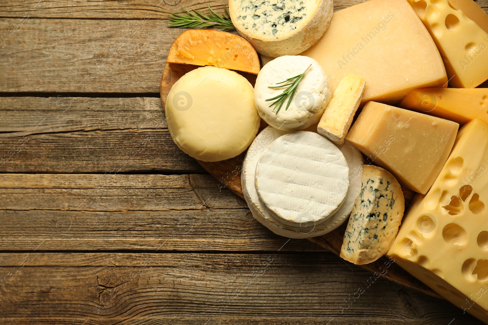 Photo of Different types of cheese on wooden table, top view. Space for text