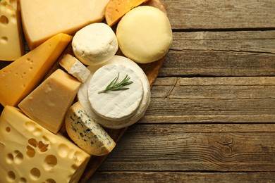 Photo of Different types of cheese on wooden table, top view. Space for text