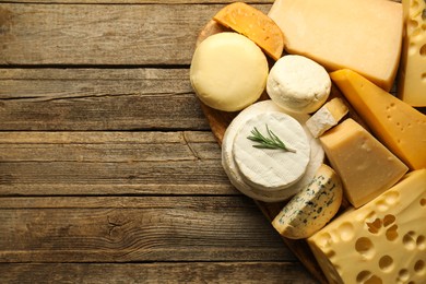 Photo of Different types of cheese on wooden table, top view. Space for text