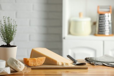 Photo of Different types of cheese, slicer and potted thyme on wooden table indoors. Space for text