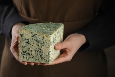 Photo of Woman with piece of delicious cheese on black background, closeup