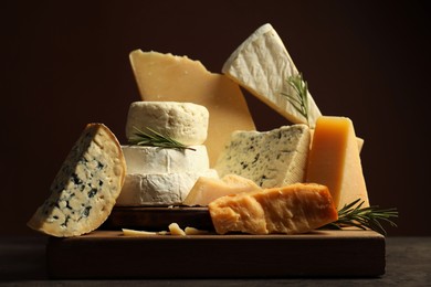 Photo of Different types of cheese and rosemary on table