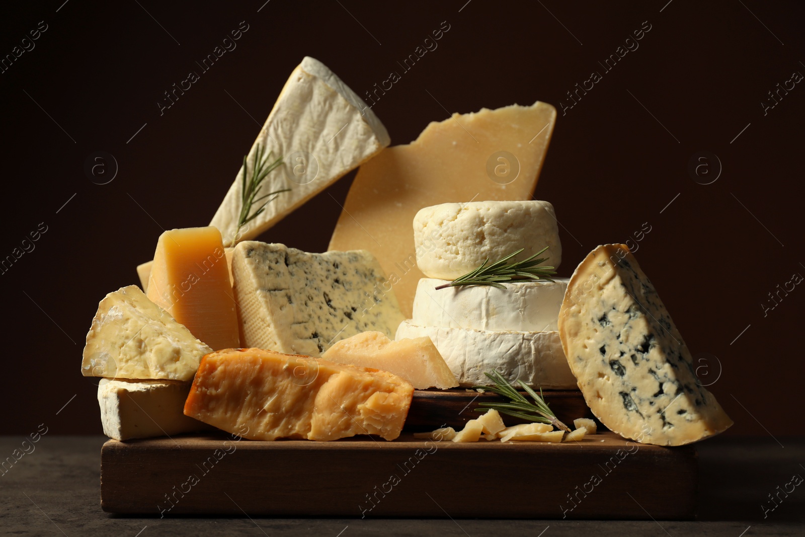 Photo of Different types of cheese and rosemary on grey table