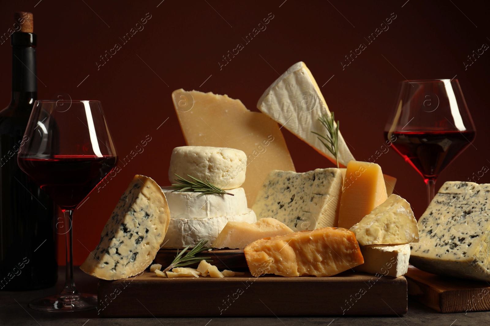 Photo of Different types of cheese, rosemary and wine on table