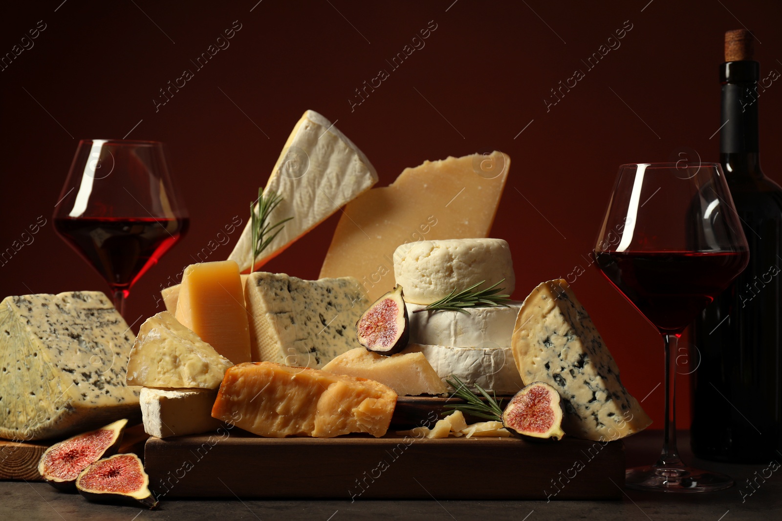 Photo of Different types of cheese, rosemary, figs and wine on table