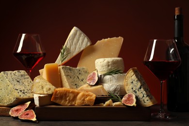 Photo of Different types of cheese, rosemary, figs and wine on table