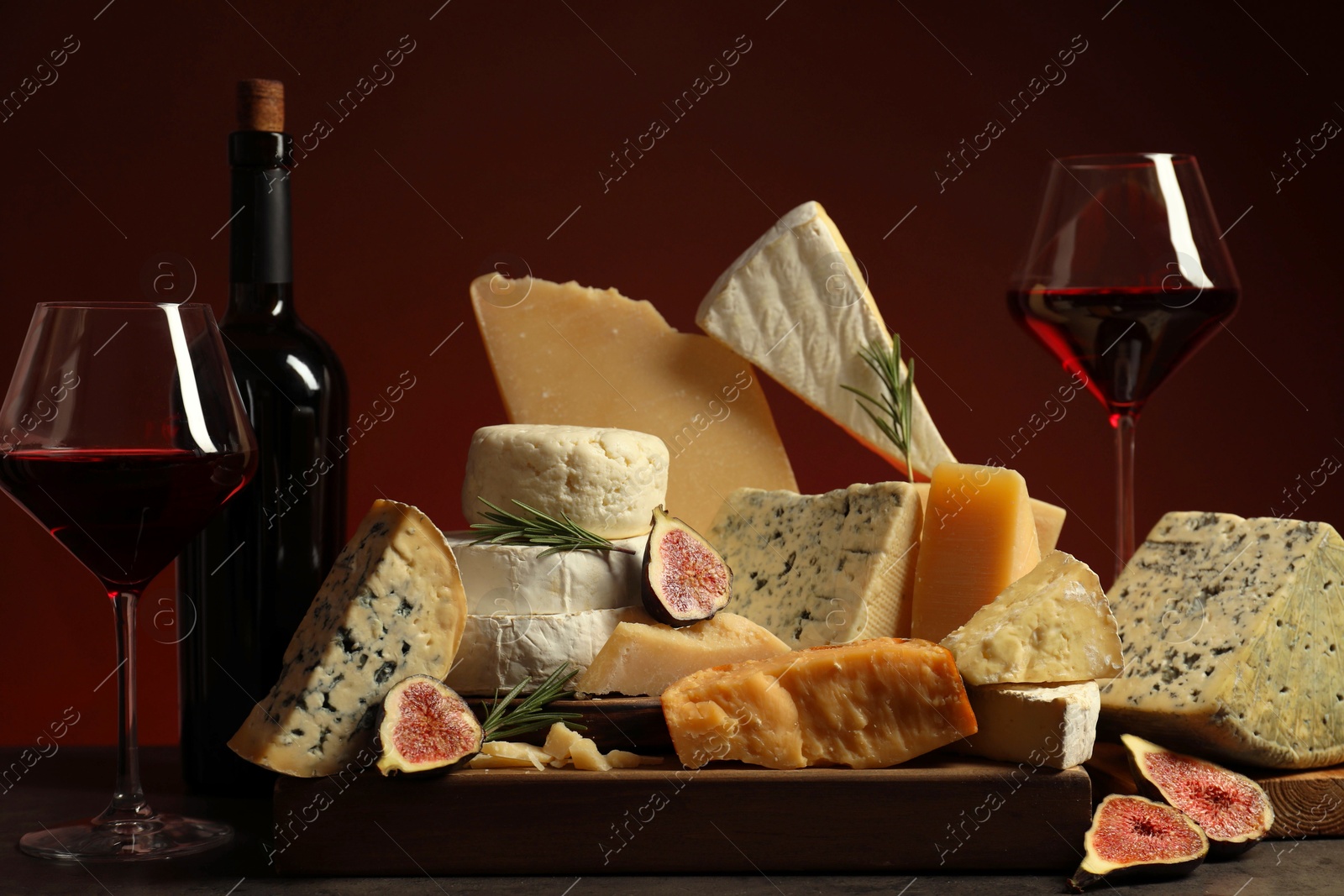 Photo of Different types of cheese, rosemary, figs and wine on table