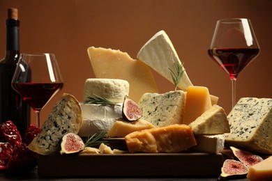 Photo of Different types of cheese, rosemary, figs, pomegranate and wine on table