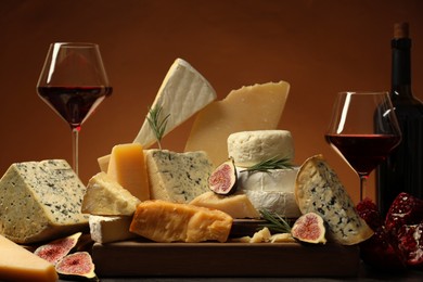 Photo of Different types of cheese, rosemary, figs, pomegranate and wine on table