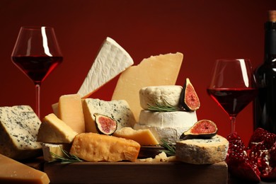 Photo of Different types of cheese, rosemary, figs, pomegranate and wine on table