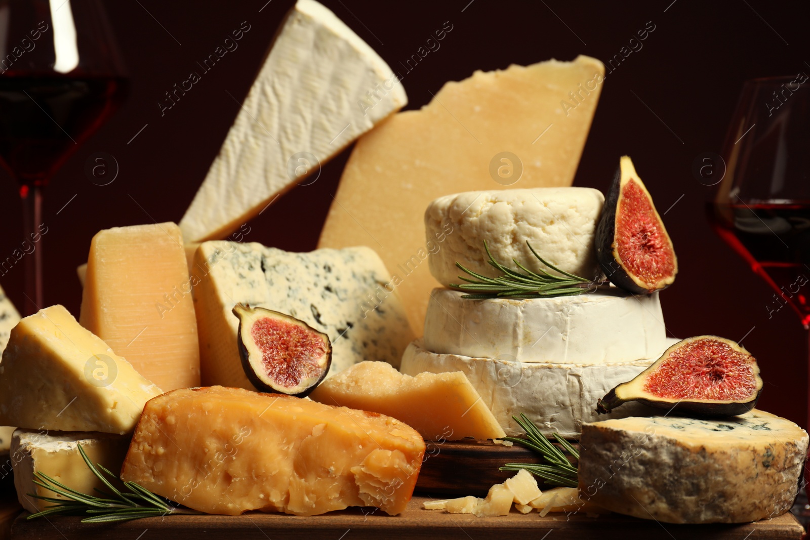 Photo of Different types of cheese, rosemary, figs and wine on table, closeup