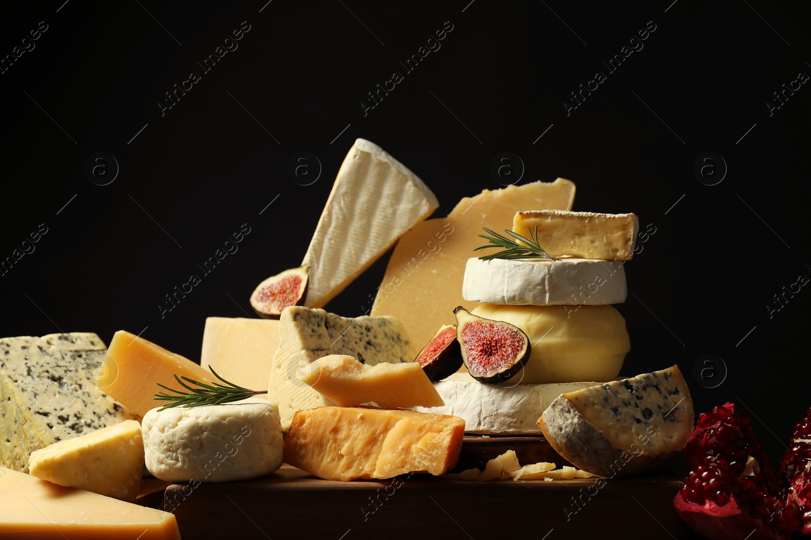 Photo of Different types of cheese, rosemary, figs and pomegranate on table