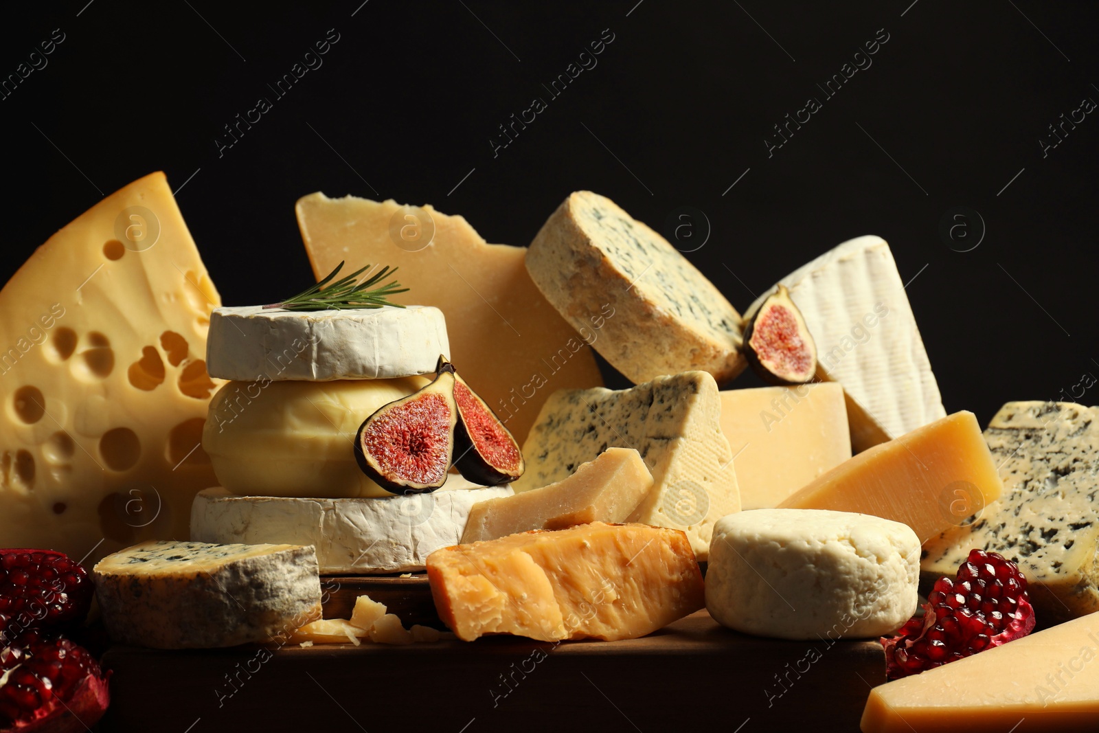 Photo of Different types of cheese, rosemary, figs and pomegranate on table