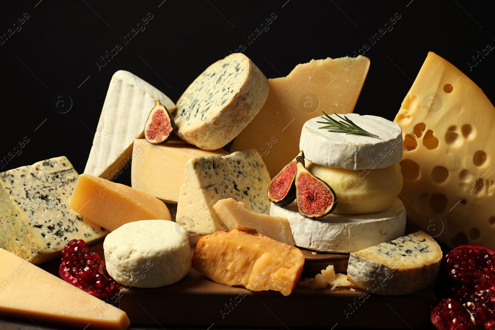 Photo of Different types of cheese, rosemary, figs and pomegranate on table