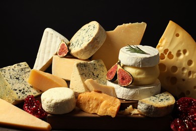 Photo of Different types of cheese, rosemary, figs and pomegranate on table