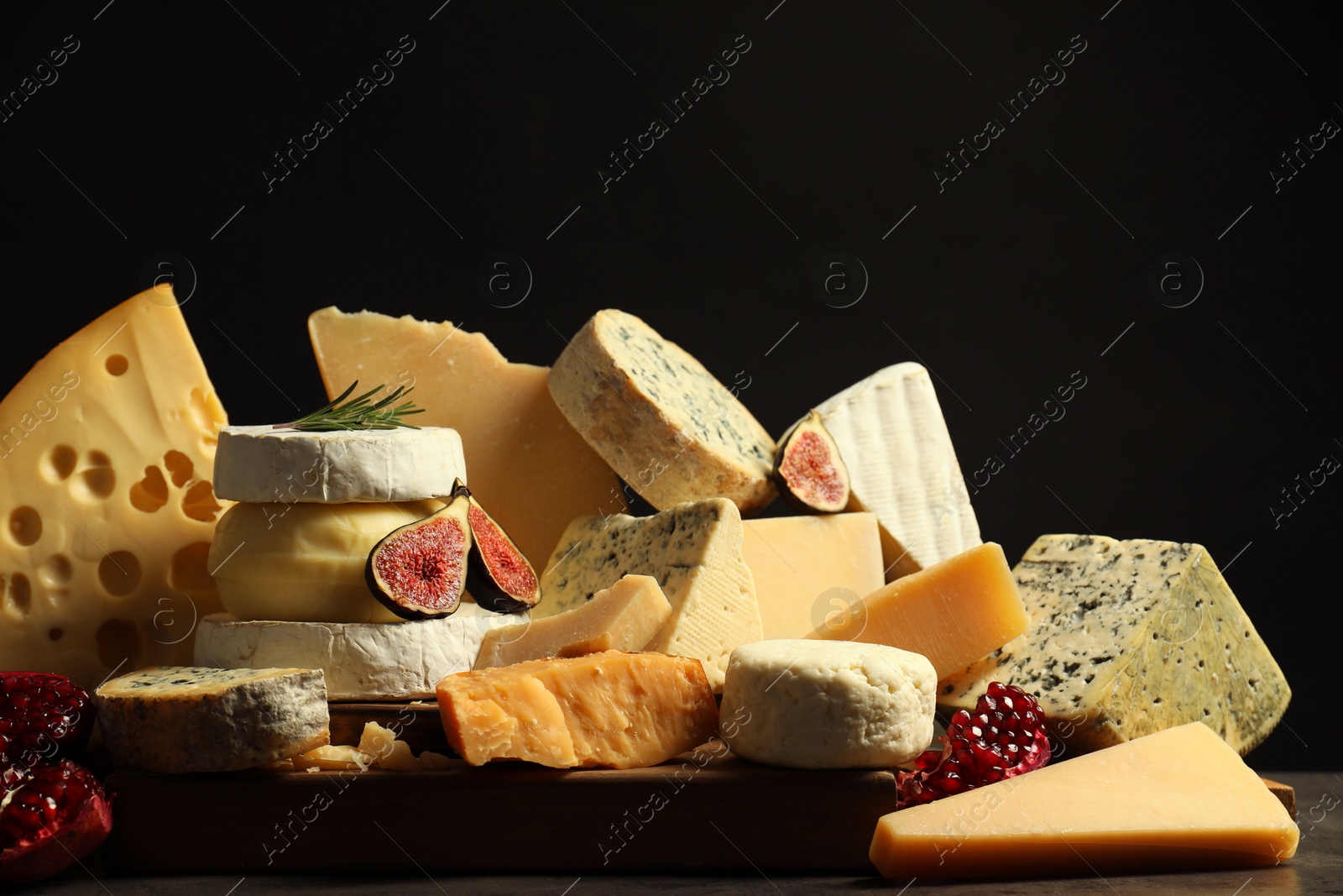 Photo of Different types of cheese, rosemary, figs and pomegranate on table