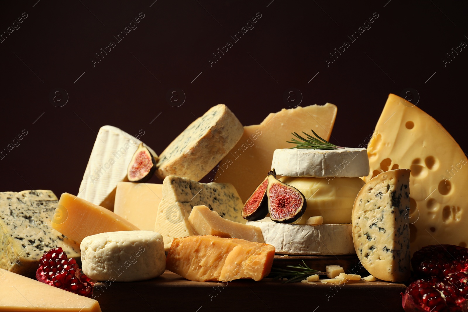 Photo of Different types of cheese, rosemary, figs and pomegranate on table