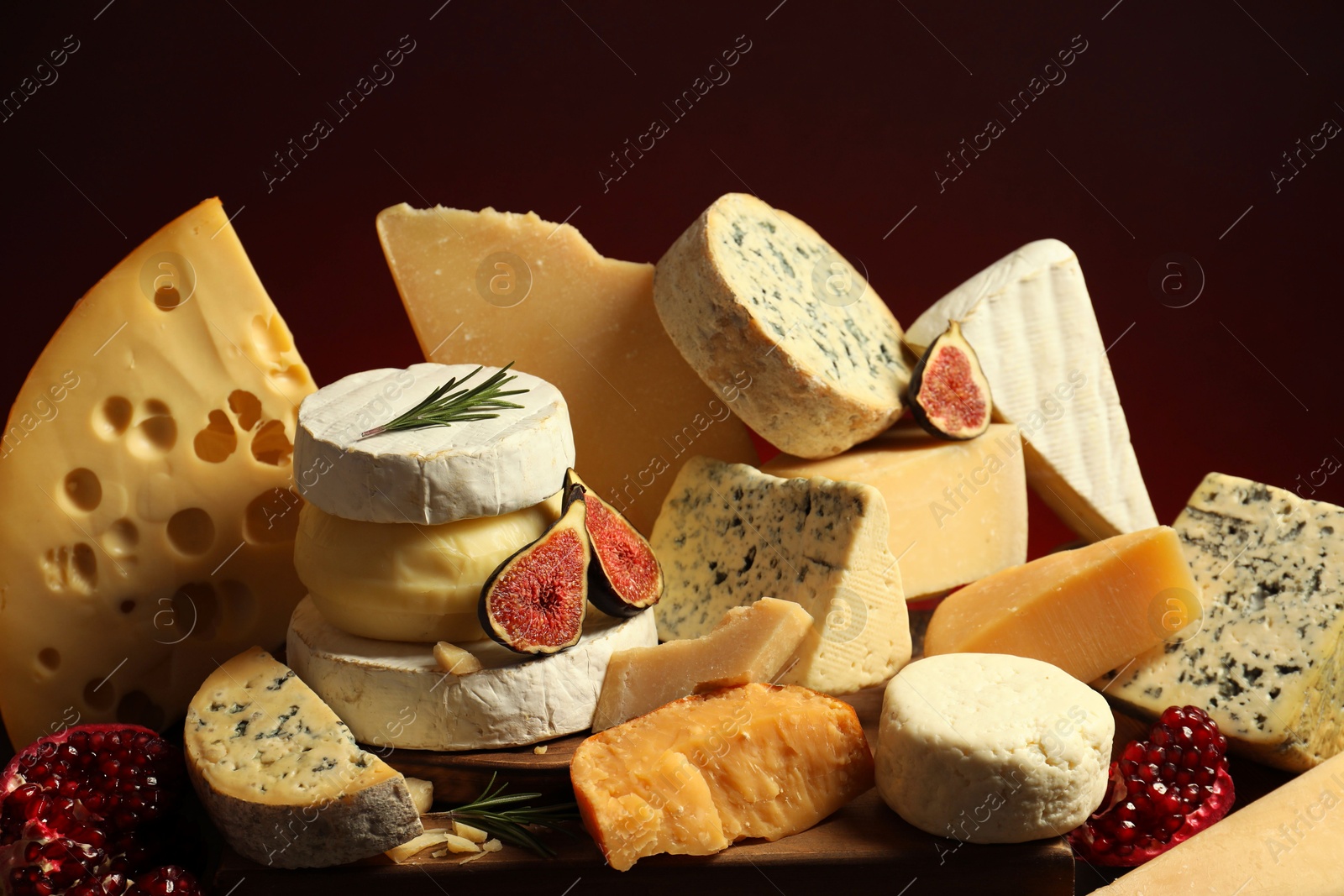 Photo of Different types of cheese, rosemary, figs and pomegranate on table