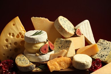 Photo of Different types of cheese, rosemary, figs and pomegranate on table