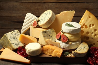 Photo of Different types of cheese, rosemary, figs and pomegranate on table